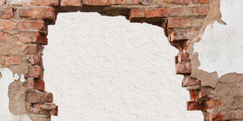A brick wall with a hole broken through