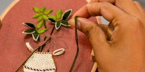 Close up of hands embroidering leaves